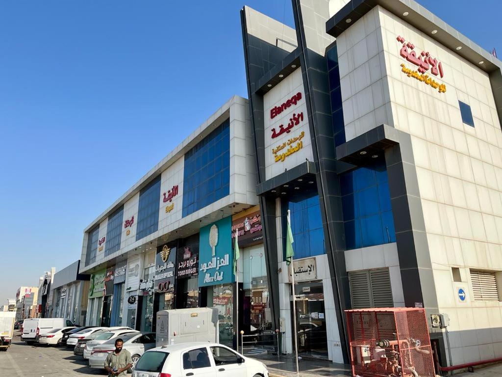 un gran edificio con coches estacionados en un estacionamiento en Al-Aniqa Furnished Apartments en Riad