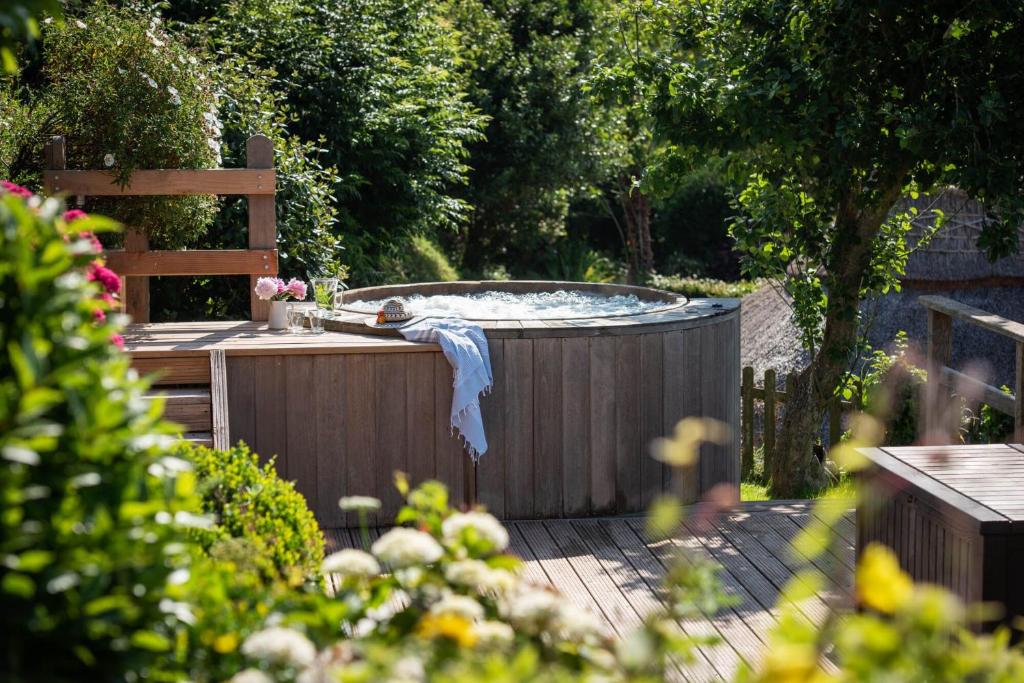 a hot tub on a wooden deck in a garden at Huckleberry Cottage in Hope-Cove