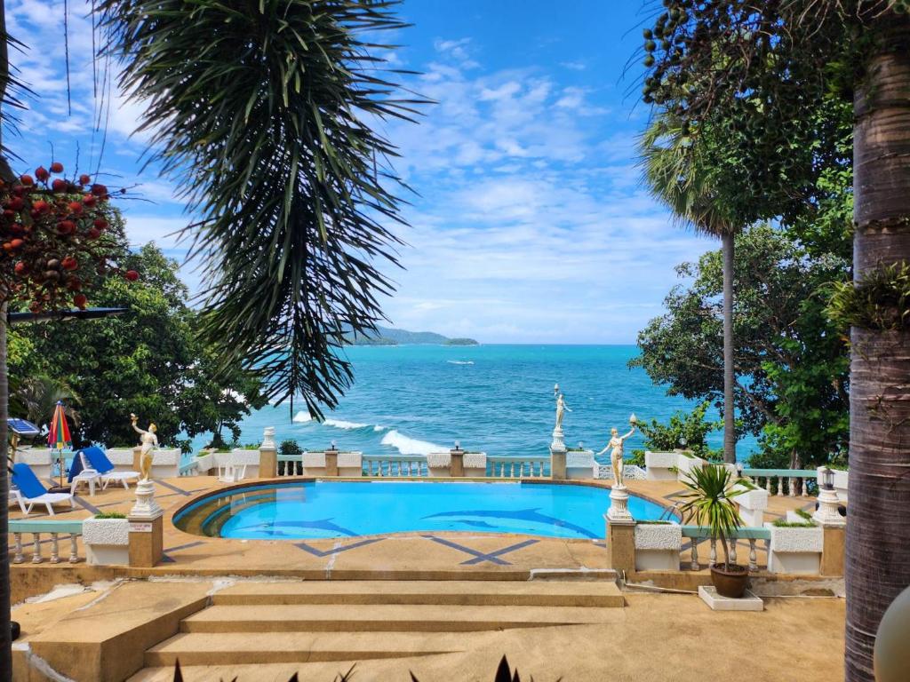 a swimming pool with the ocean in the background at Baan Karon Hill Phuket Resort in Karon Beach