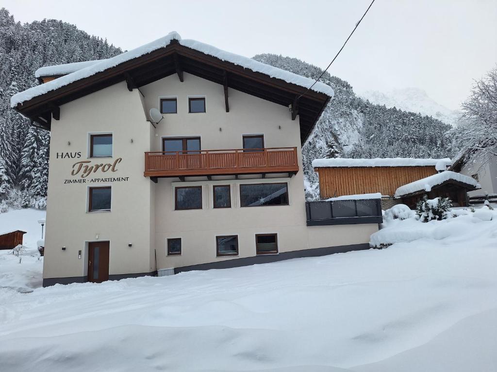 a building with snow on the ground in front of it at Appartements Tyrol in Pettneu am Arlberg