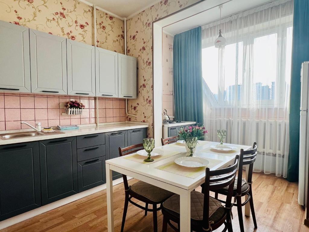 uma cozinha com uma mesa e cadeiras brancas e um lavatório em Cozy three-room apartment with Mountain view em Almaty