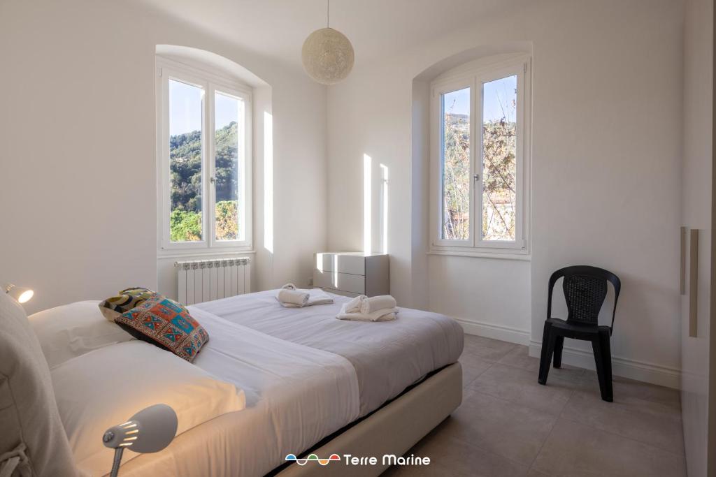 a white bedroom with a bed and two windows at BlueGreen in La Spezia