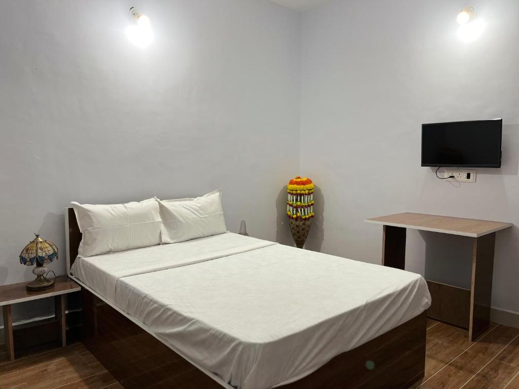 a bedroom with a bed with a tv on a wall at Lotus Guest House in Kharakvasla