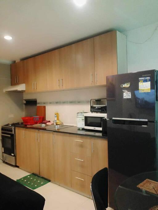 uma cozinha com armários de madeira e um frigorífico preto em Boracay Apartment unit 5 em Boracay