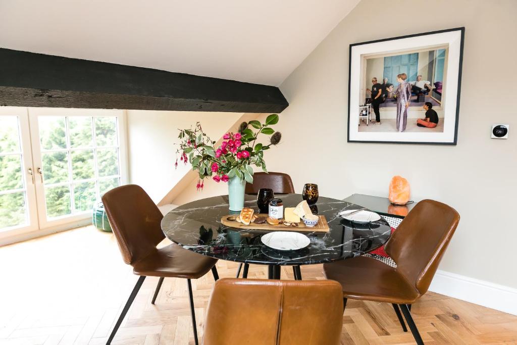 une salle à manger avec une table noire et des chaises brunes dans l'établissement The Sky Lodge & Penthouse Apartments at Hillthorpe Manor by Maison Parfaite - Wentbridge, à East Hardwick