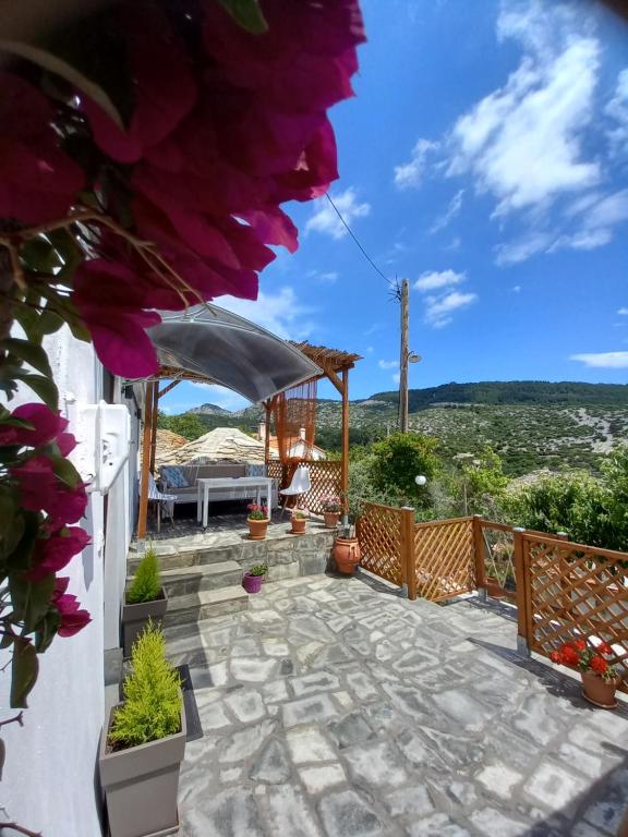 - une terrasse avec une table, des chaises et des fleurs dans l'établissement Panthea Residence, à Theológos