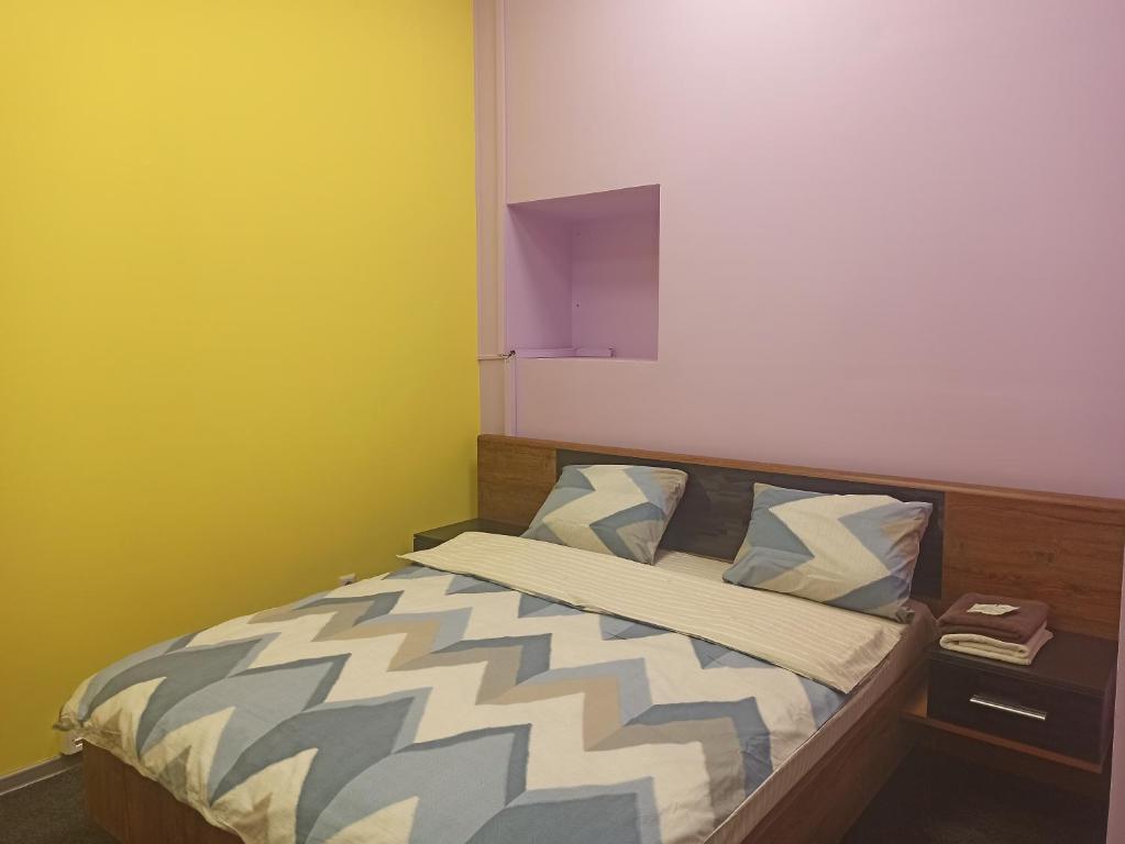 een klein bed in een kamer met gele muren bij Старий Дворик,кімнати біля жд вокзалу in Lviv