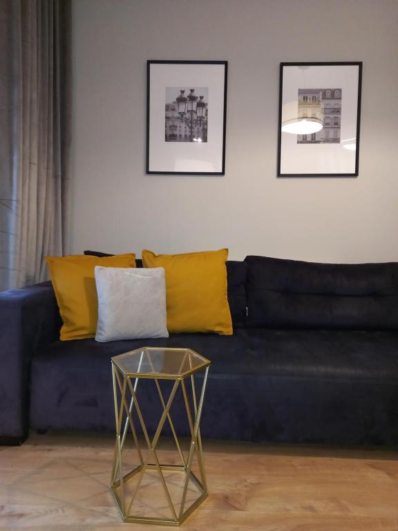 a blue couch with yellow pillows and a glass table at Apartament Łąkoszyn Kutno in Kutno