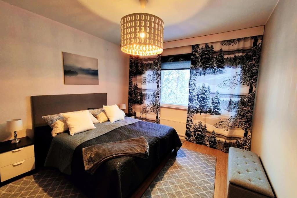 Un dormitorio con una cama grande y una lámpara de araña. en Spacious apartment with balcony and free WiFi, en Rovaniemi