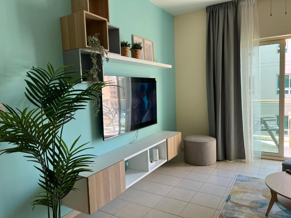 sala de estar con TV de pantalla plana en la pared en Nice Location - 76 m2, en Dubái
