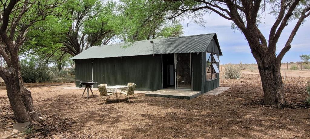 a small green building with a table and a grill at Soetdorings Farmstay Karoo Chalet in Beaufort West