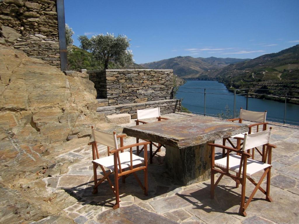 una mesa de madera y sillas en un patio de piedra con un lago en Quinta Da Marka, en Covas do Douro