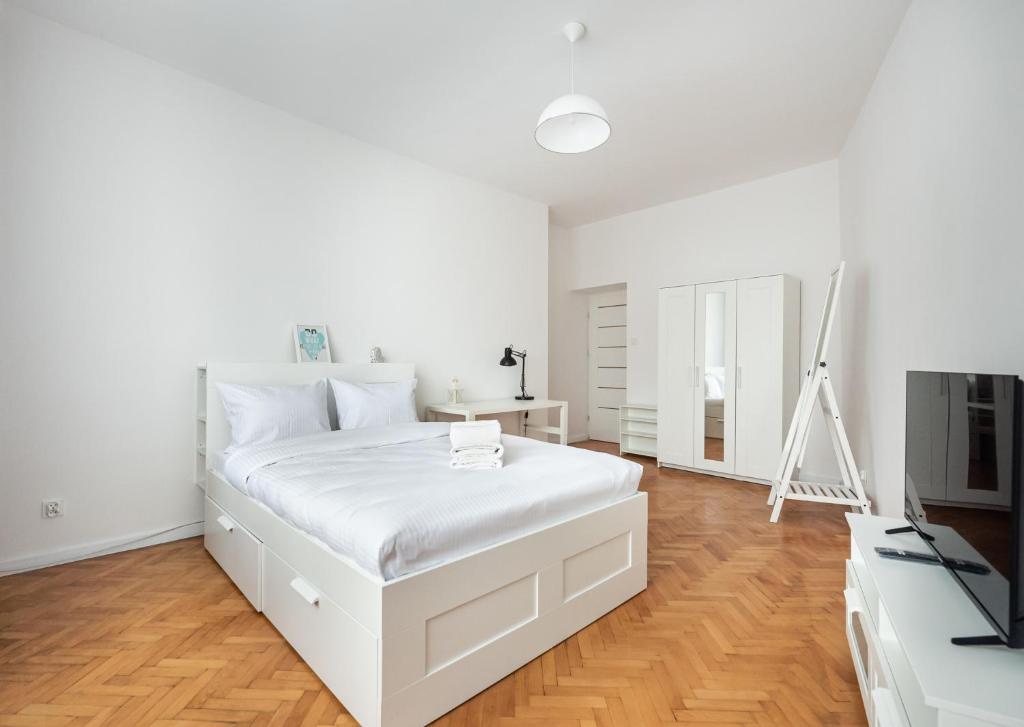 ein weißes Schlafzimmer mit einem weißen Bett und einem TV in der Unterkunft Old Town 5-Bedroom Apartment in Warschau