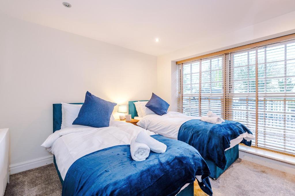 a bedroom with two beds with blue sheets and a window at Stunning 4-bedroom Country House with Canal Views in Sandbach by HP Accommodation in Sandbach