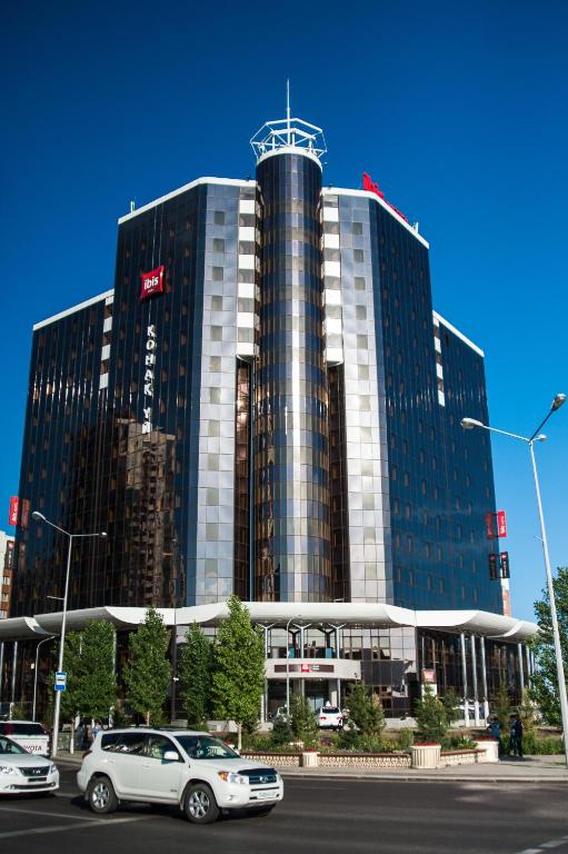 a large building with cars parked in front of it at Ibis Astana in Astana