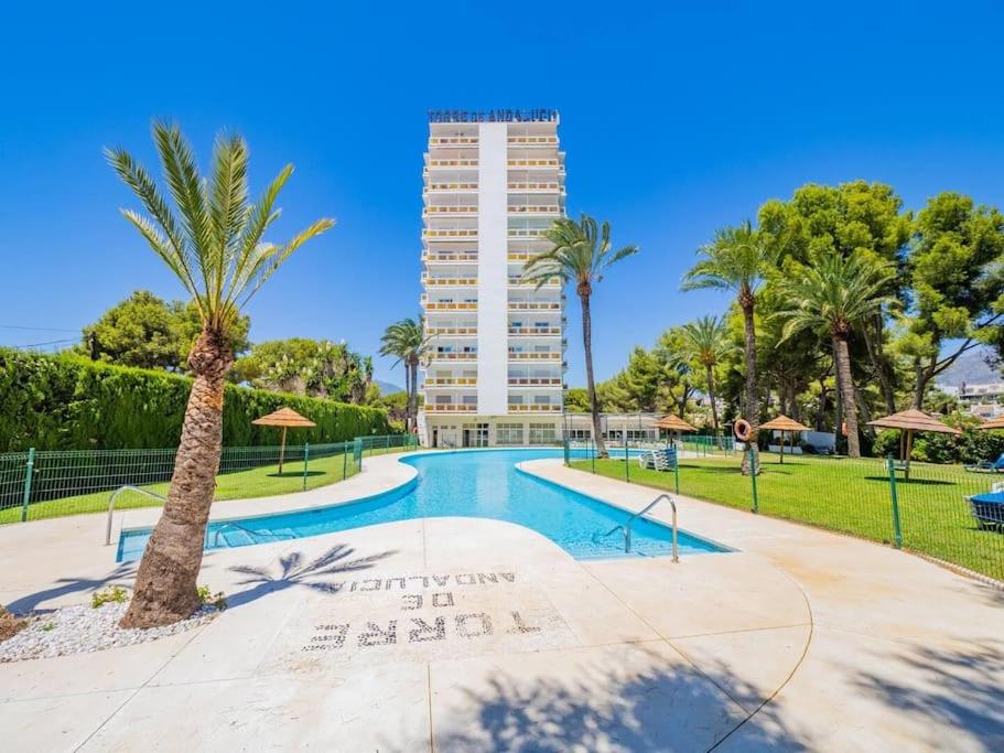 une piscine bordée de palmiers et un grand bâtiment dans l'établissement Estudio Torre de Andalucía, à Marbella