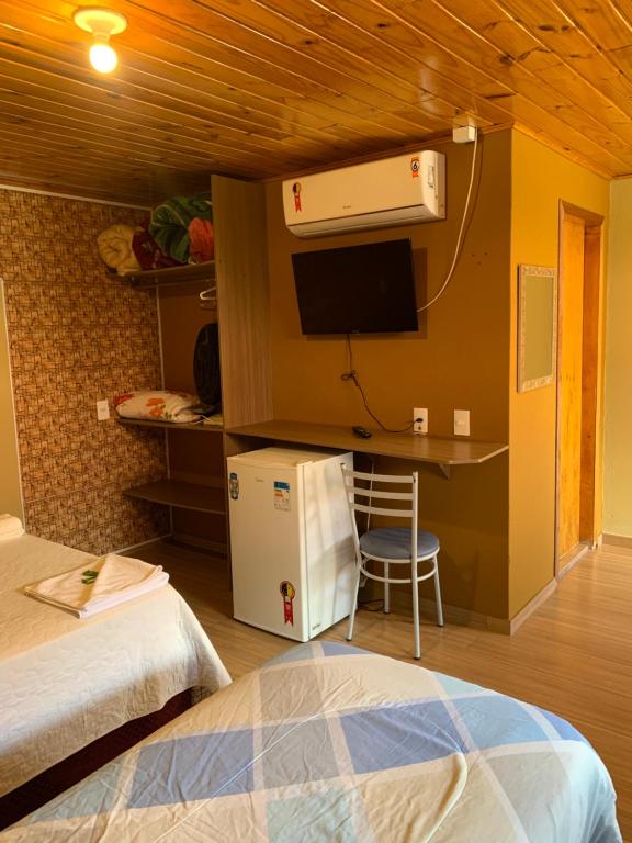 a room with a bed and a desk and a refrigerator at Pousada avenida in Urubici