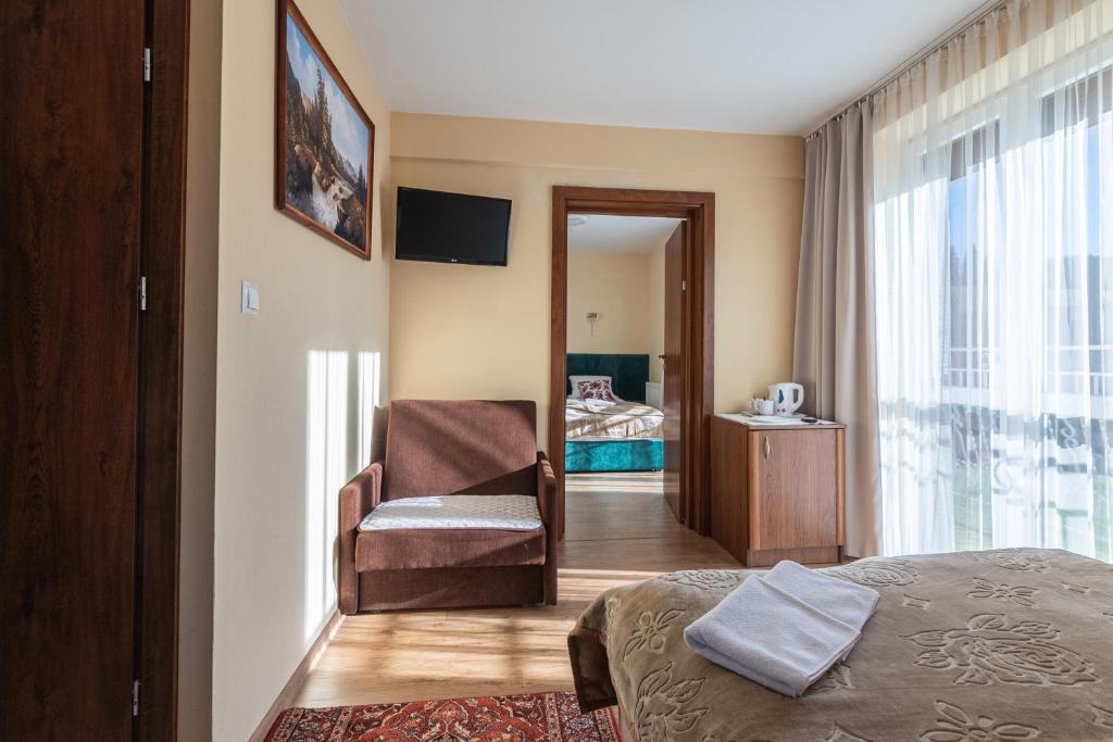 een slaapkamer met een bed, een stoel en een raam bij Tylicki Zdrój in Tylicz