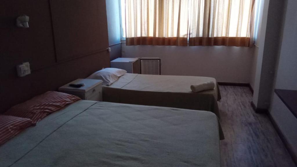 a hotel room with two beds and a window at HOTEL CRONOS in Villa Carlos Paz