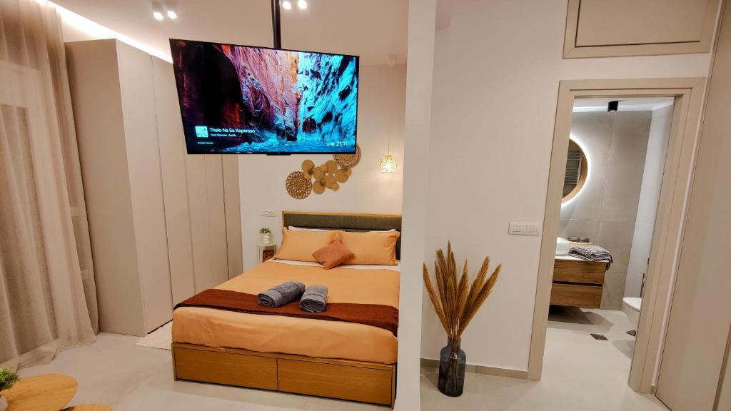 Elpis' cozy & luxury apartment في أثينا: غرفة نوم مع سرير وتلفزيون على الحائط