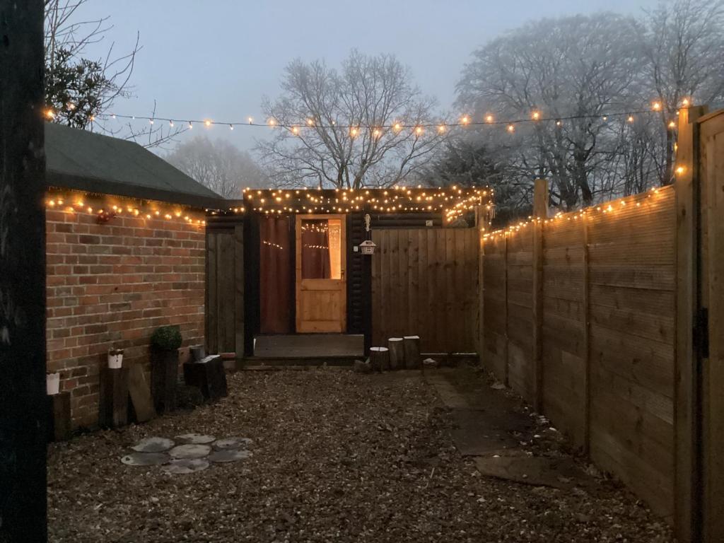 a fence with christmas lights in front of a door at Cabin 4 in Kent