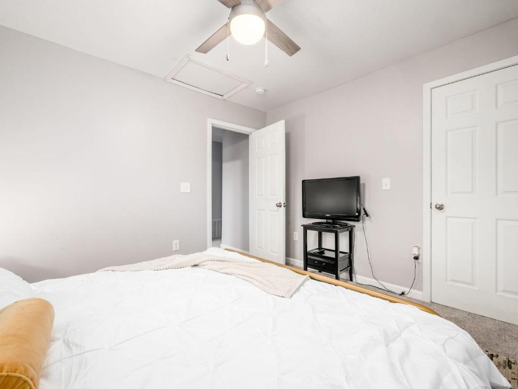 a white bedroom with a bed and a flat screen tv at Staying Comfortable in Central Columbus, Pet Friendly, 30 Day Min Stay in Columbus