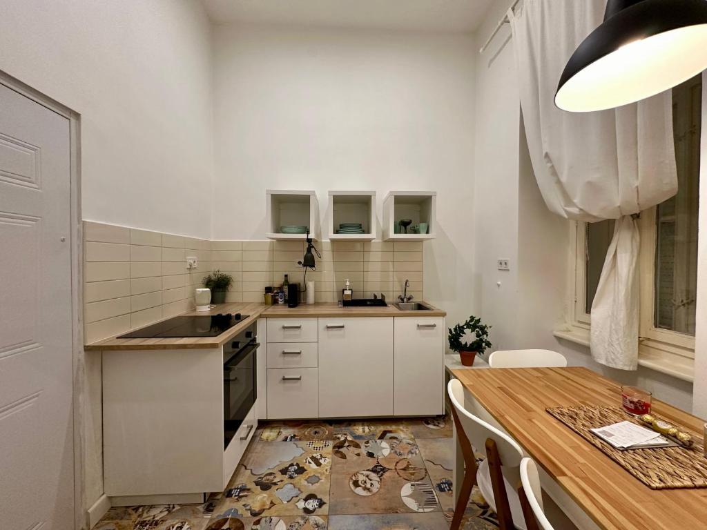 cocina con armarios blancos y mesa de madera en Cozy studio flat in the heart of Budapest, en Budapest