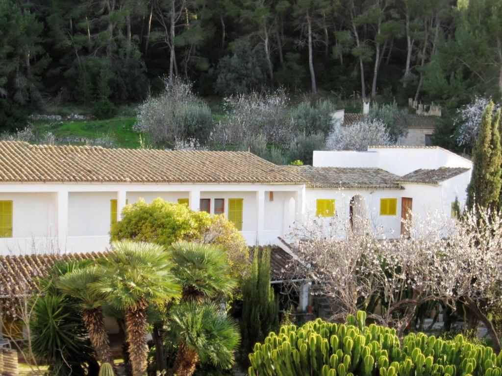 a white house with yellow doors and trees at Hostal Catalina Vera in Port d’Andratx