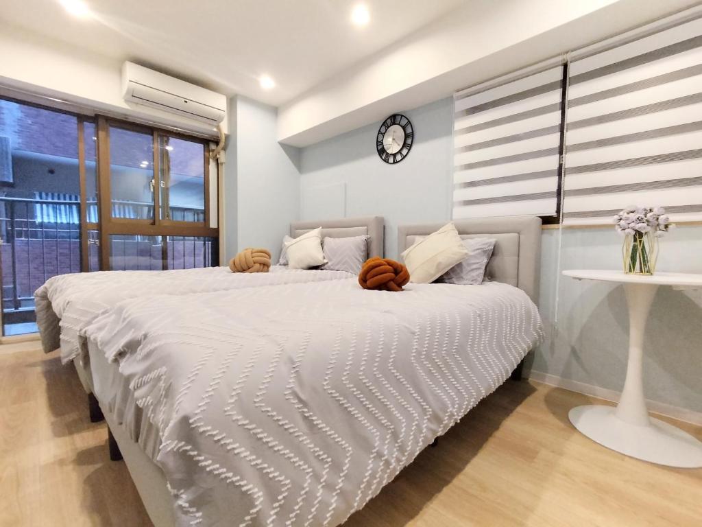 a bedroom with a large bed with a clock on the wall at S21新宿最中心 東新宿站5分-Shinjuku center 5 mins to Station, Max 3P 直达新宿 涉谷 表参道 池袋 上野 代代木 银座 原宿 in Tokyo