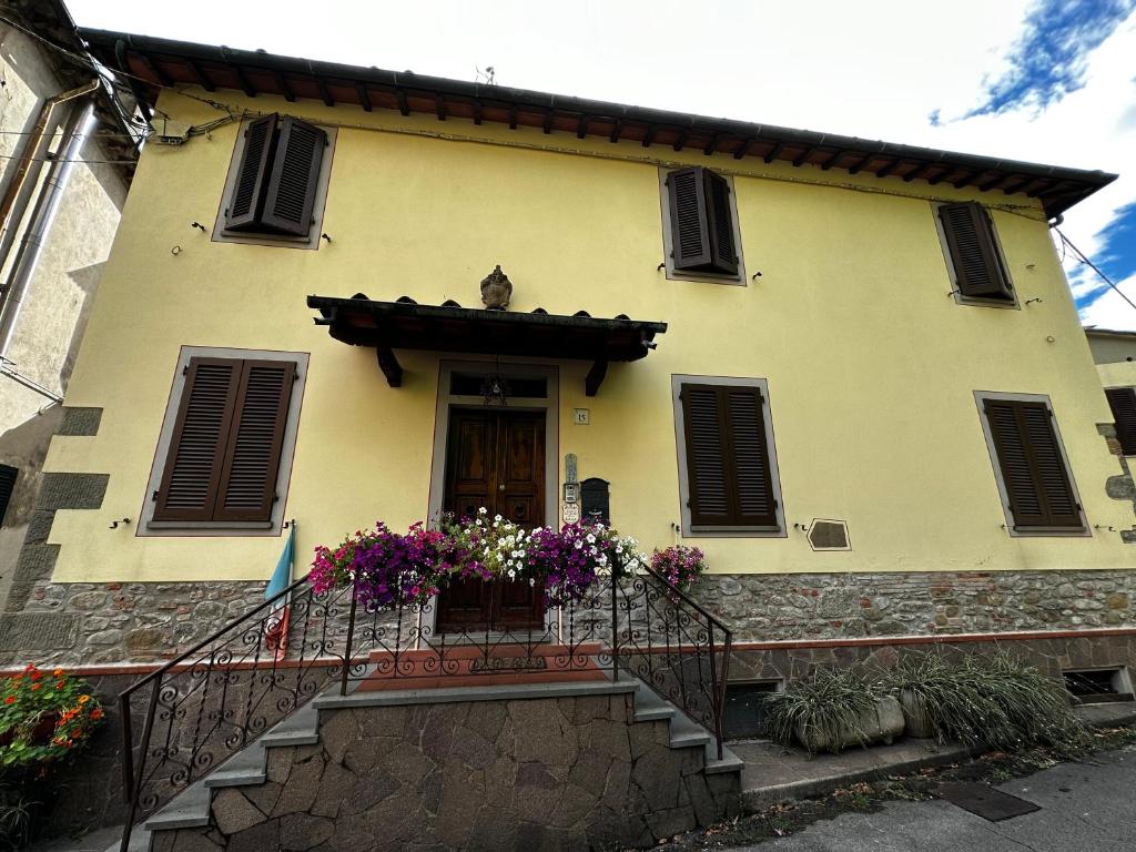 une maison jaune avec un balcon fleuri dans l'établissement A COLLODI IO & MAMMA, à Collodi