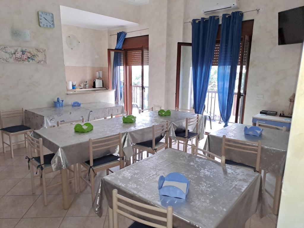 ein Esszimmer mit Tischen und Stühlen und blauen Vorhängen in der Unterkunft G&G - Bed & Breakfast in Vieste