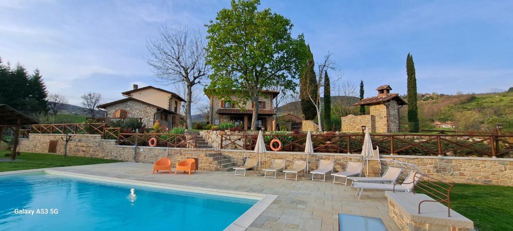 a swimming pool with chairs and a house in the background at L'Antico Cipresso in Poppi