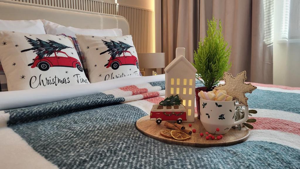 a bed with christmas themed pillows and a tray of food at Apartament Gdańska in Gdańsk