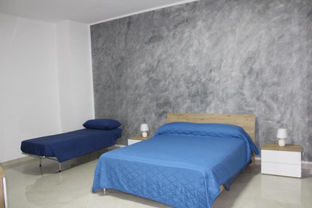 - une chambre avec 2 lits bleus et un mur en béton dans l'établissement AFFITTACAMERE MONTE OLIMPO, à Galatone