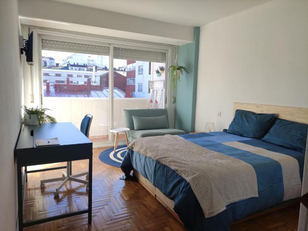 a bedroom with a bed and a desk and a window at Apartamento confort urzaiz vigo. in Vigo