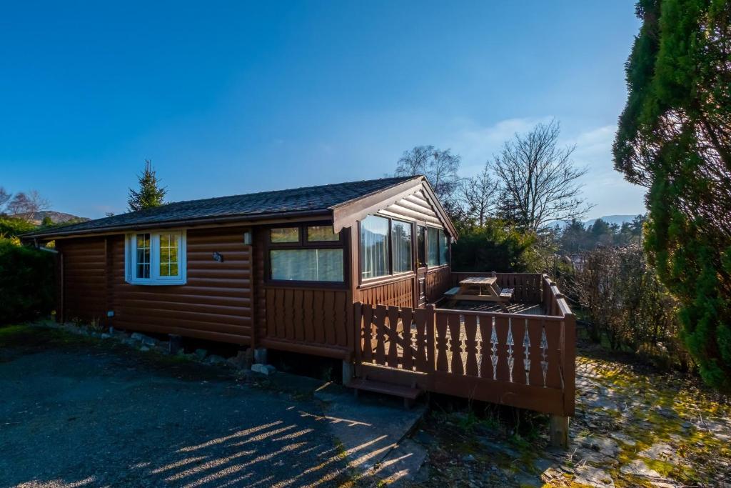 a wooden cabin with a large window and a deck at Cosy Log Cabin Snowdonia Eryri in Trawsfynydd