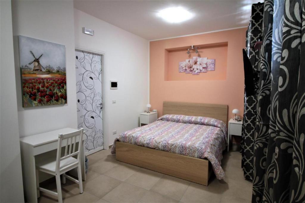 a bedroom with a bed and a desk and a door at La Rosatea Rooms in Monreale