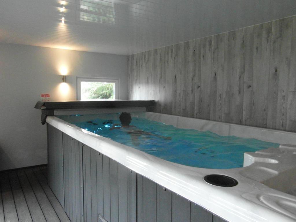a person swimming in a large tub in a bathroom at Amazing cottage with private indoor swim pool and hot tub in Grantown on Spey