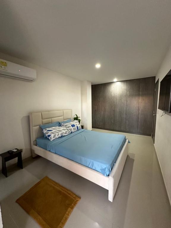 a bedroom with a bed with blue sheets and a wooden wall at Lindo apartamento cerca de Centro Comercial unico in Barranquilla