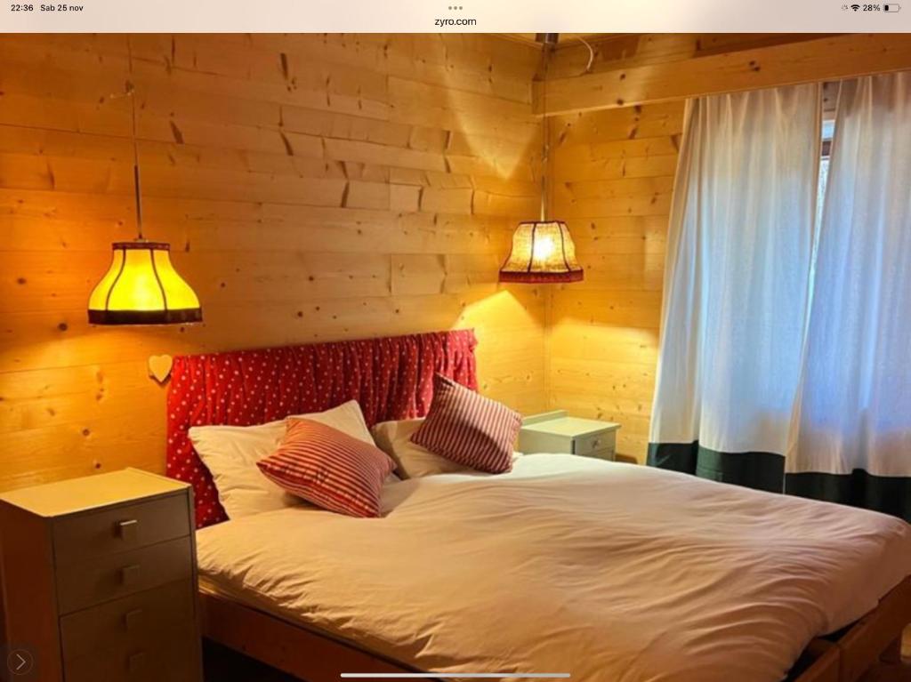 a bedroom with a large bed with two lamps at Baita cavalese giardino esclusivo in Cavalese