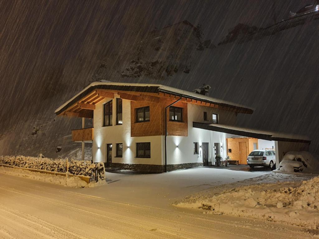 a house in the snow with a car parked in front at Anni, Apart in Tux