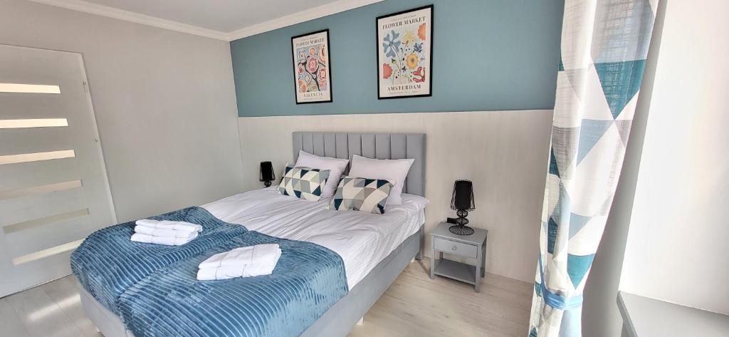 a bedroom with a bed with a blue and white blanket at Apartament Wileńska 15 in Sejny