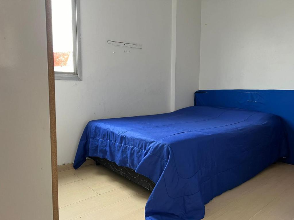 a blue bed in a white room with a window at Apartamento para Eventos Autódromo de Interlagos ou região in Sao Paulo