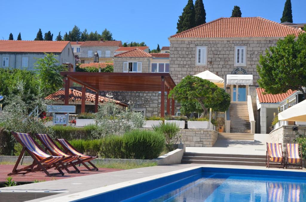 una piscina con sillas y una casa en Hotel Borik, en Lumbarda