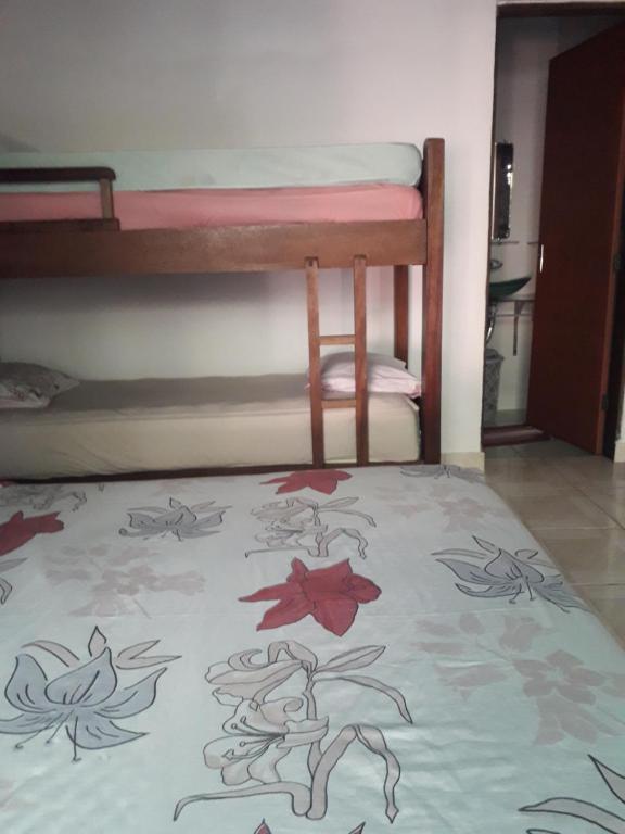 a bedroom with bunk beds and a bed with a blanket at Casa familiar no paraíso Guaraú. in Peruíbe