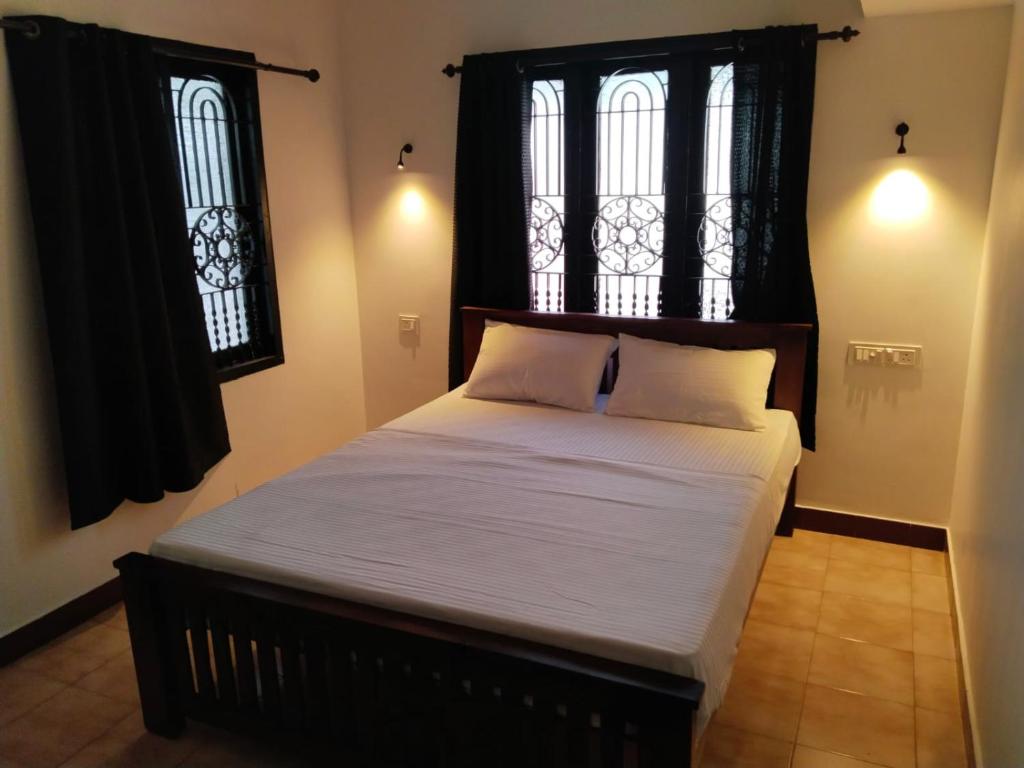 a large bed in a room with two windows at The Chill House in Cochin