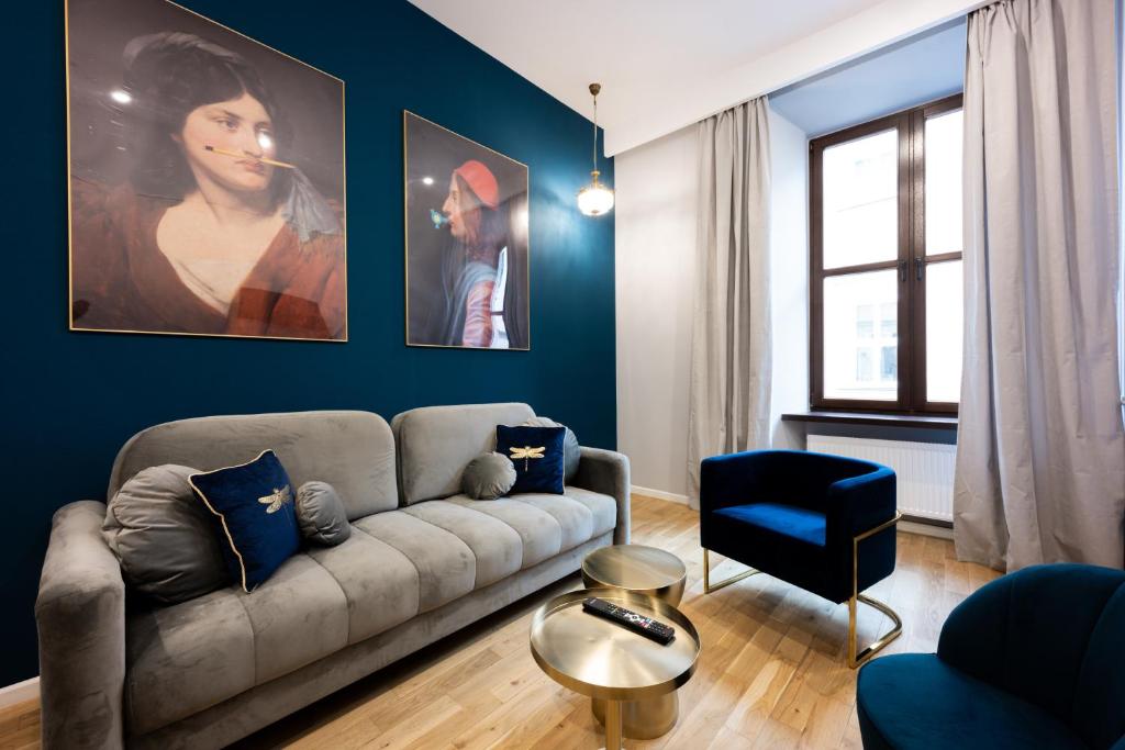 Una sala de estar con un sofá y una pared azul. en Bracka Main Square Apartments, en Cracovia