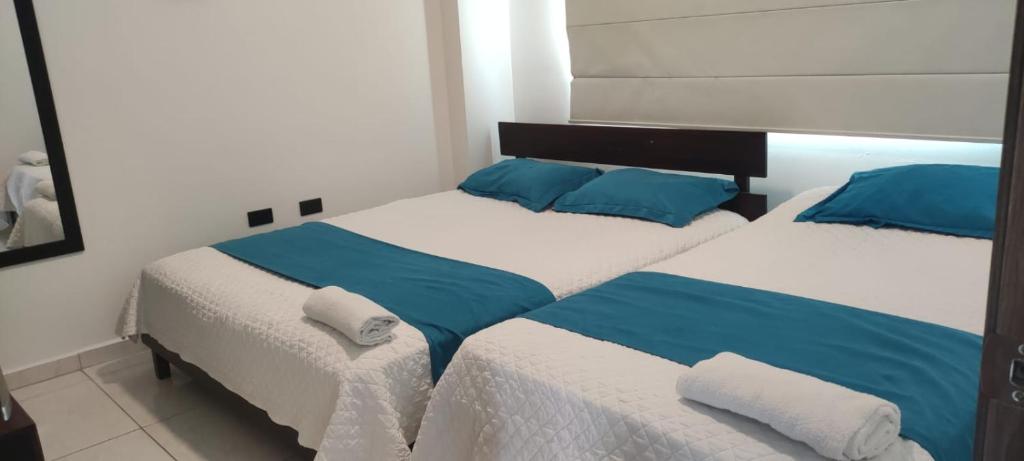 a bedroom with two beds with blue and white sheets at Hotel Mykonos Manta in Manta