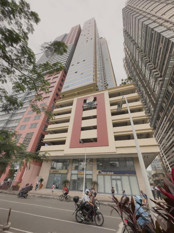 a tall building with people riding motorcycles in front of it at SnugglePod Condotel - Grand Riviera Suites in Manila