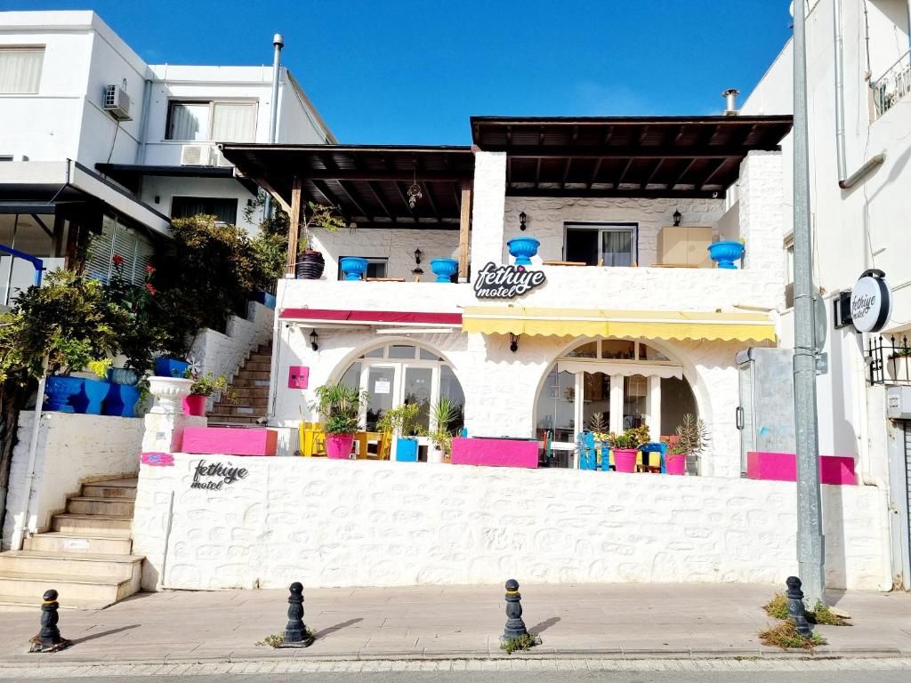 a white building with pink and blue on a street at Fethiye Motel BODRUM in Bodrum City